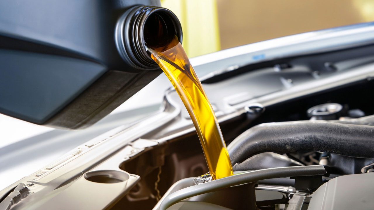 Aceite para el auto Aceite lubricante automotriz siendo vertido desde una galonera al motor de un auto.